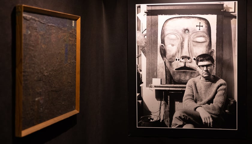 Zdzisław Beksiński siedzący przed swoim obrazem (fotografia), wystawa „Beksiński we Wrocławiu”