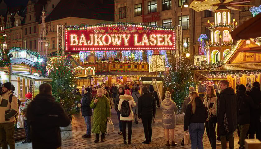 Jarmark Bożonarodzeniowy we Wrocławiu. Widać przechodniów oraz szyld z napisem "Bajkowy Lasek"