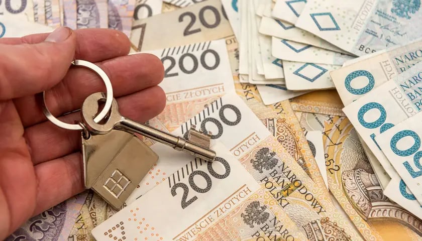 Banknoty 200- i 50-złotowe oraz złoty klucz do mieszkania w dłoni. Czy 4 października RPP zdecyduje ponownie o obniżce stóp procentowych.