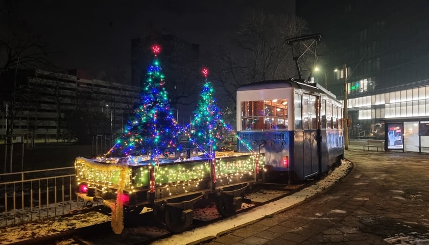 Zabytkowy tramwaj z choinkami świątecznymi na lorze transportowej
