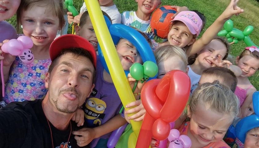Piknik osiedlowy. Na zdjęciu widać dorosłego mężczyznę i dzieci z balonami