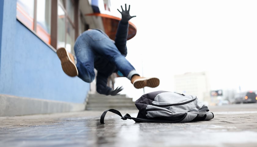 Przewracający się na śliskim chodniku mężczyzna. Przez najbliższe dni na ulicach i chodnikach we Wrocławiu może być bardzo ślisko. 