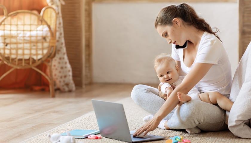 Kobieta z małym dzieckiem siedząca przy laptopie