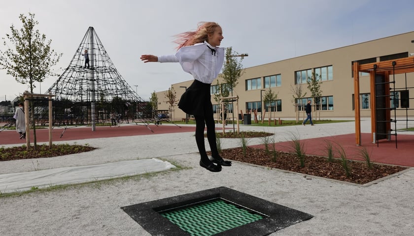 Dziewczynka skacząca na trampolinie przy szkole na Asfaltowej. To właśnie w tym budynku powstanie w tym roku jedno z nowych Centrów Aktywności Lokalnej (CAL). Zdjęcie ilustracyjne, wykonane w dniu rozpoczęcia roku szkolnego.