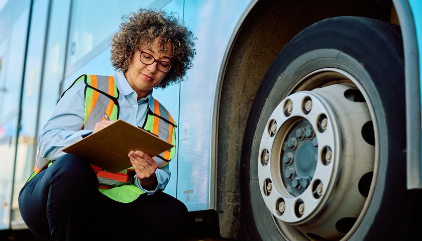 Kobieta przy kole autokaru pisze w notatniku, zdjęcie ilustracyjne