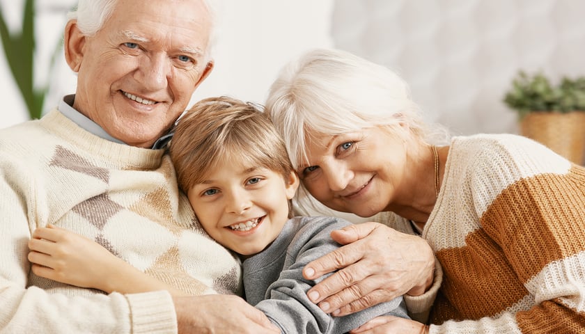 Na zdjęciu uśmiechnięta babcia i dziadek z wnuczkiem / zdjęcie ilustracyjne