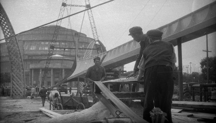 Na pierwszym planie robotnicy, w tle budynek. Rok 1948 r. Zdjęcie ilustracyjne. 