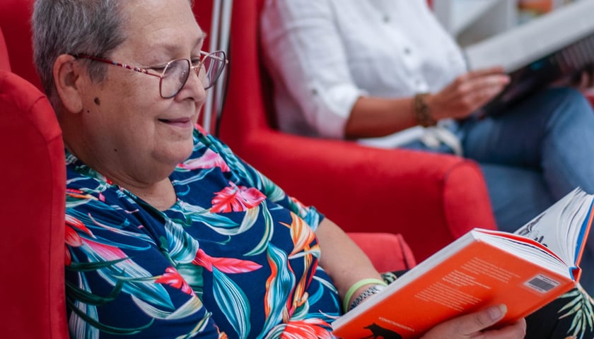Wrocławscy seniorzy będą czytać dzieciom bajki. Na zdjęciu dwie siedzące w fotelach kobiety z książkami