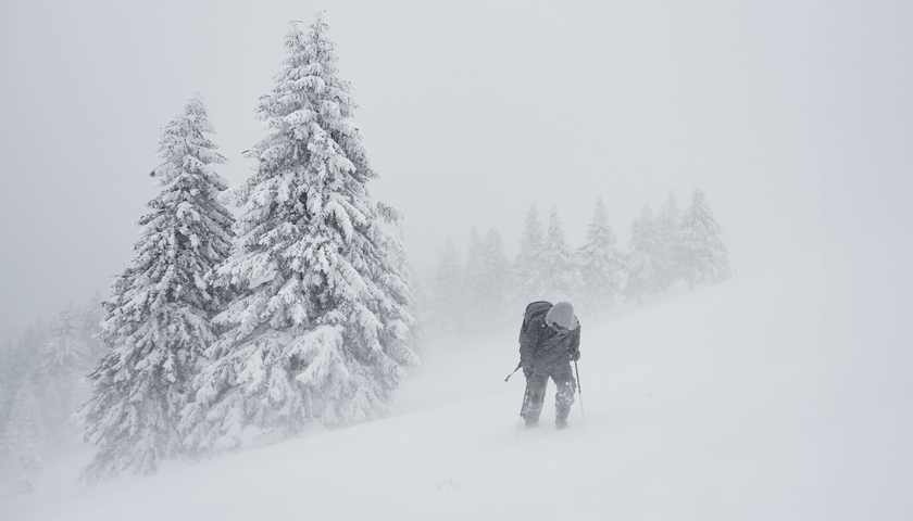 Mężczyzna idący w zadymce śnieżnej w górach. Zdjęcie ilustracyjne
