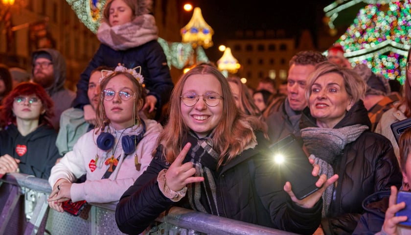 Światełko do Nieba w Rynku podczas Finału WOŚP. Publiczność przed sceną. Na pierwszym planie młoda dziewczyna z telefonem