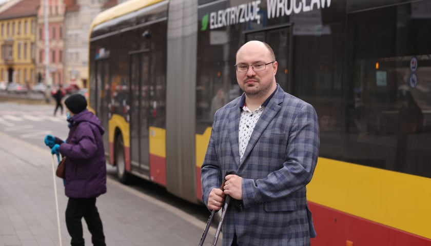 Michał Sałkowski, zastępca dyrektora Wydziału Transportu UM na tle autobusu MPK. 