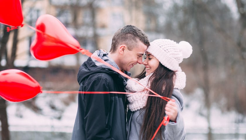 Para w parku, kobieta trzyma w ręce balony w kształcie serca