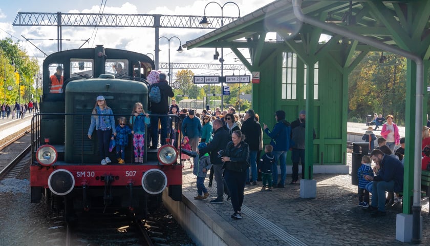 Zabytkowy pociąg na stacji. Widać też ludzi zwiedzających lokomotywę i stojących na peronie