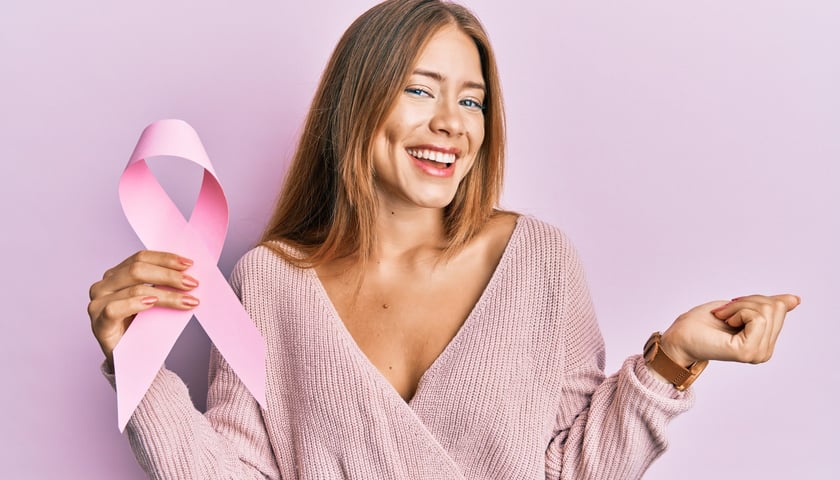 Uśmiechnięta kobieta z różową wstążką w ręku / zdjęcie ilustracyjne
