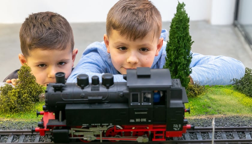 Dwóch chłopców patrzy na miniaturowy model pociągu w Modelarni Kolejkowo