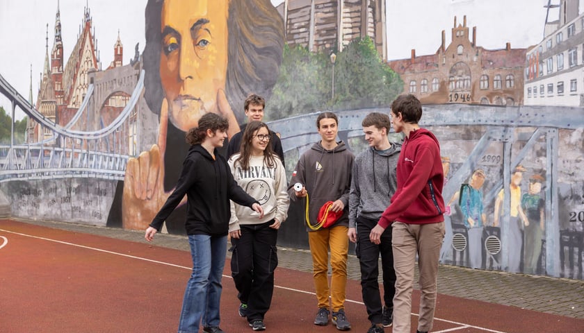 Szóstka uczniów przed muralem z Adamem Mickiewiczem w III LO