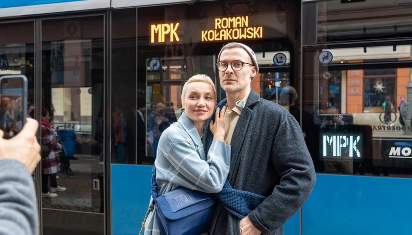 Kobieta i mężczyzna przed tramwajem z napisem Roman Kołakowski