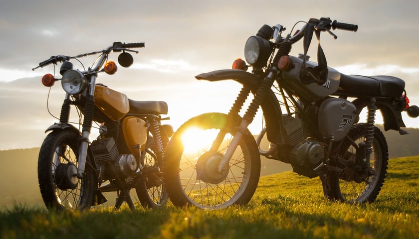 Na zdjęciu dwa motocykle na łące w świetle zachodzącego słońca. Sprawdź zloty i imprezy motocyklowe na Dolnym Śląsku!