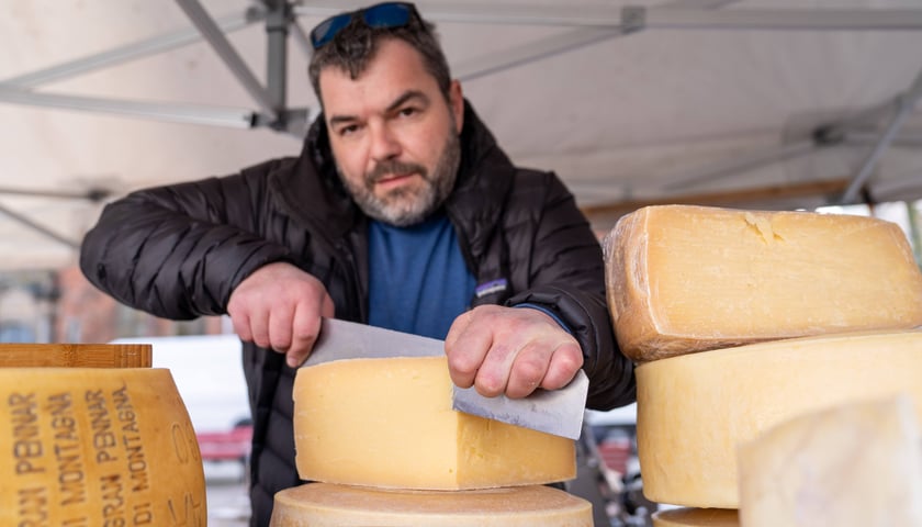 Mężczyzna kroi ser wielkim nożem