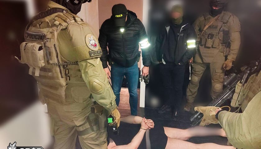 Policjanci podczas akcji CBŚP i jeden z zatrzymanych leżący na ziemi