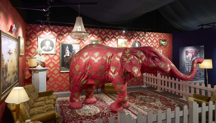 Na zdjęciu czerwony słoń w pokoju, instalacja z wystawy poświęconej Banksy'emu