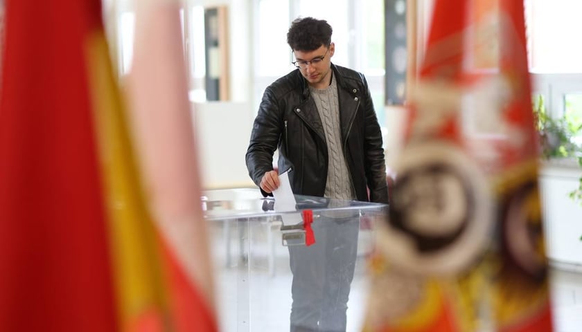 Wybory samorządowe we Wrocławiu. Na zdjęciu mężczyzna wrzucający kartę do głosowania do urny