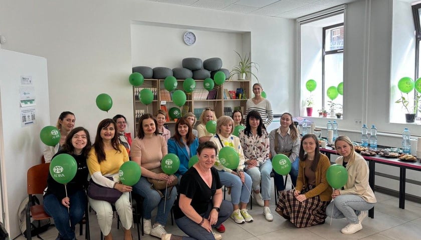Grupa kobiet z zielonymi balonikami pozująca do wspólnego zdjęcia. Spotkanie beneficjentów w Centrum Integracji Cudzoziemców we Wrocławiu.