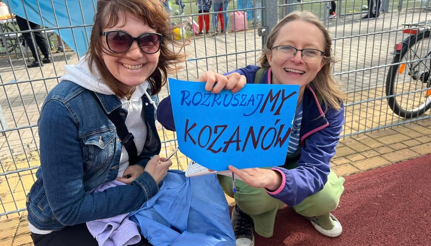 Na zdjęciu dwie kobiety trzymają niebieską kartkę z napisem "Rozruszajmy Kozanów" podczas Aktywnego Dnia na Kozanowie, wrzesień 2023