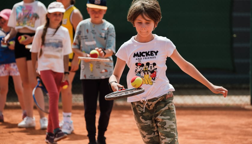Chłopiec trzyma w dłoni rakietę tenisową, a na niej piłeczkę (Półkolonie w WCT Spartan tenis-rolki) 