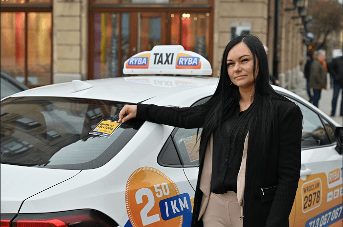 Jowita Dąbrowska z firmy Ryba Taxi przy swojej taksówce