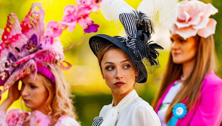 Trzy kobiety w elegenackich kreacjach i nakryciach głowy podczas Ladies Day na Partynicach w roku 2023