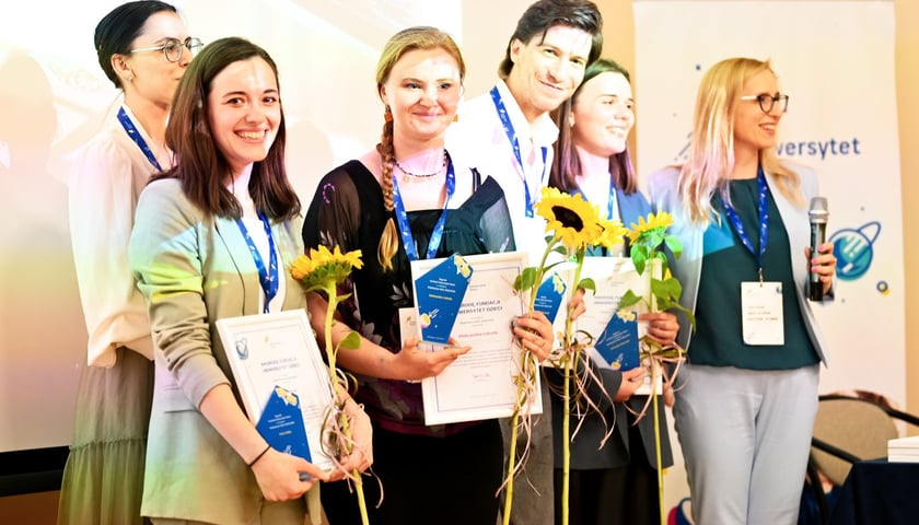 Kobiety i mężczyzna z kwiatami, laureaci Fundacji Uniwersytet Dzieci 