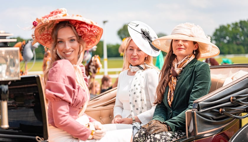 Suempol Ladies Day  na Partynicach. Wrocław, 09.06.2024. Na zdjęciu trzy kobiety w eleganckich strojach siedzące w konnym powozie.
