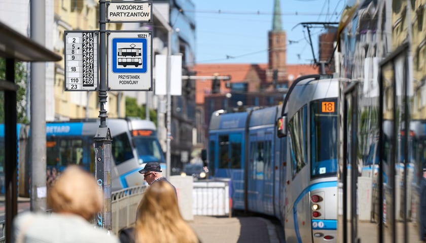 Trójka pasażerów, autobus i tramwaje przy przystanku Wzgórze Partyzantów, czerwiec 2024