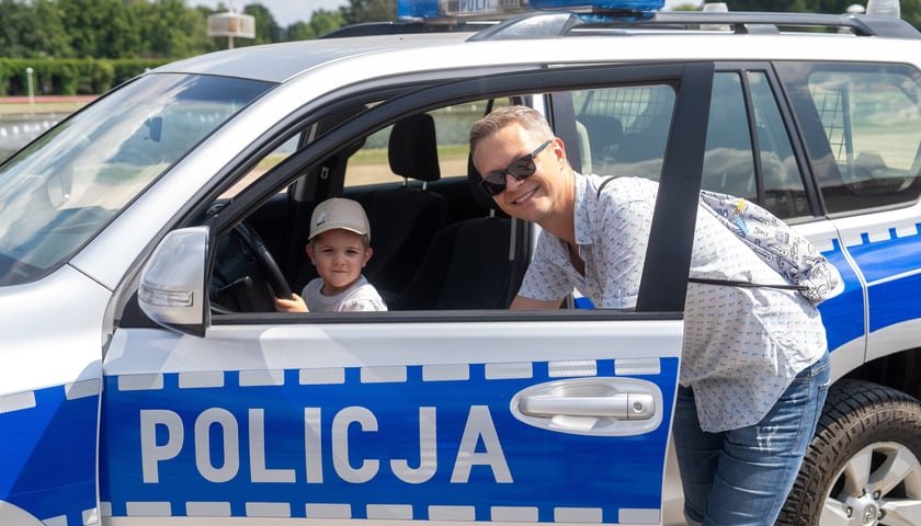 Chłopiec z tatą przy policyjnym radiowozie