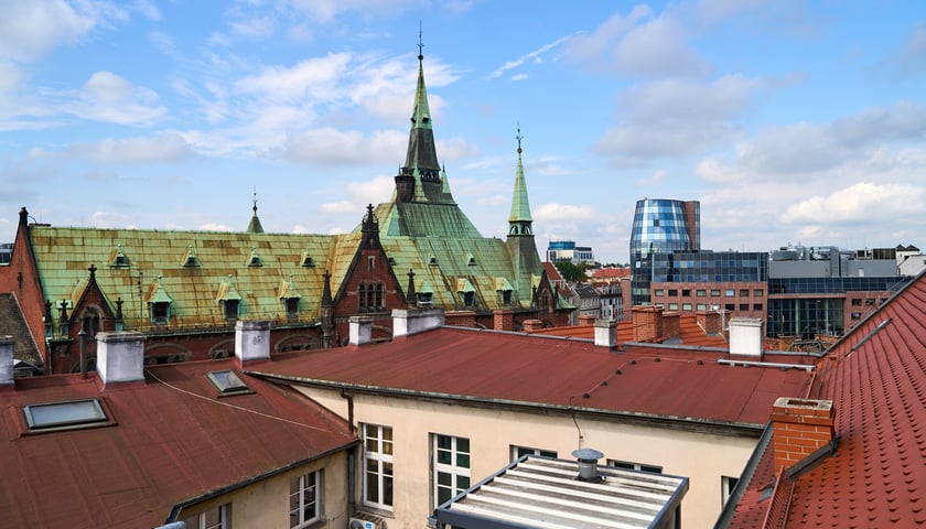 Widok z kamienicy na pl. Solnym. Widać dachy kamienic, wieżę budynku dawnej Biblioteki Uniwersyteckiej przy Szajnochy i Kino Nowe Horyzonty. 