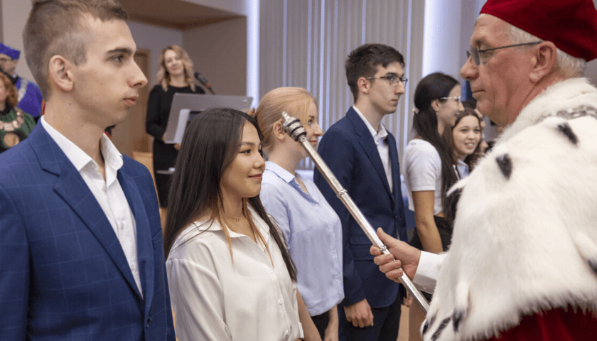 Rektor pasuje nowych studentów Uniwersytetu Przyrodniczego, kładąc na ramieniu każdego z nich berło. Inauguracja roku akademickiego 2023/2024