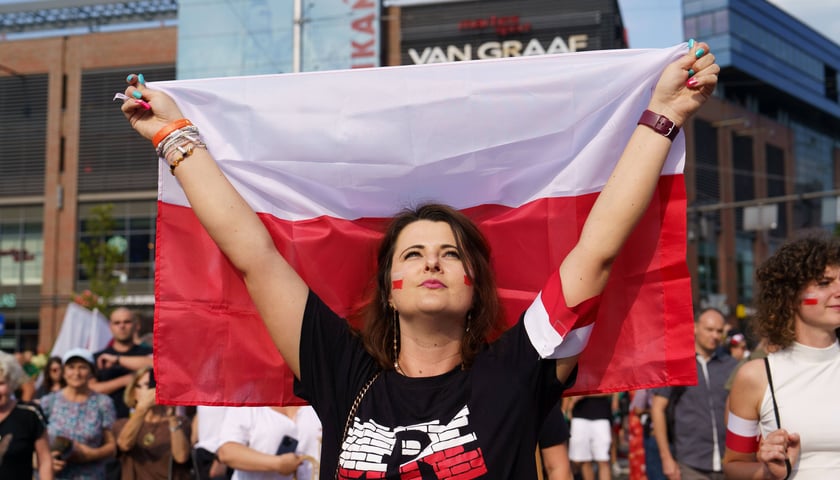 Godzina "W" we Wrocławiu. Jedna z uczestniczek obchodów na pl. Dominikańskim (kobieta trzyma polską flagę) 