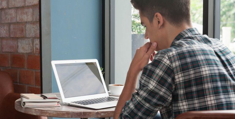 młody mężczyzna siedzący przed komputerem, zdjęcie ilustracyjne