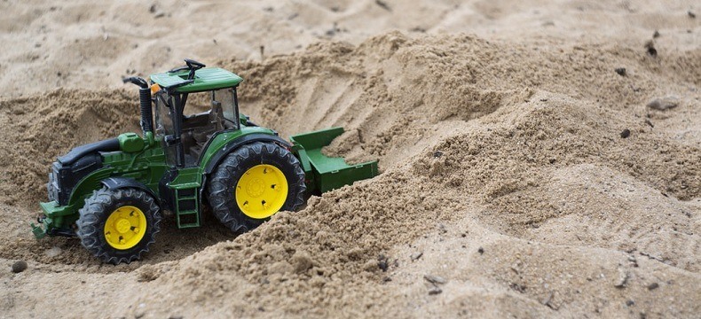 zielony zabawkowy traktor w piaskownicy, zdjęcie ilustracyjne