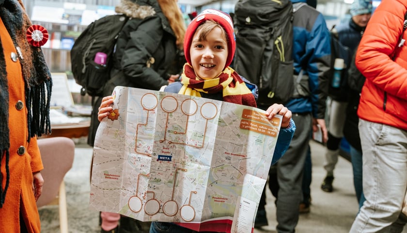 Zdjęcie ilustracyjne: WrocWalk 2023. Na pierwszym planie uśmiechnięty chłopiec z mapą