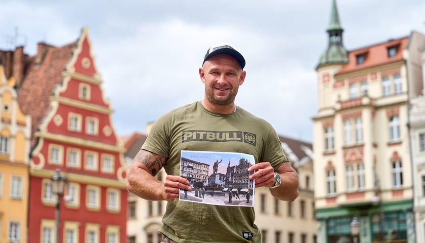 Mężczyzna trzymający w rękach zdjęcie na placu Solnym. Łukasz Stelmach od pięciu lat prowadzi na Facebooku profil „Mój dawny Wrocław”.