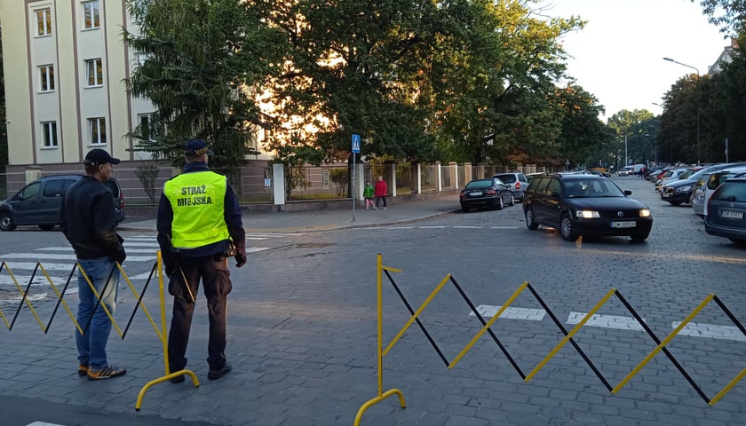 Straż miejska zamyka ulicę i pilnuje przejścia dla pieszych w okolicy szkół podstawowych