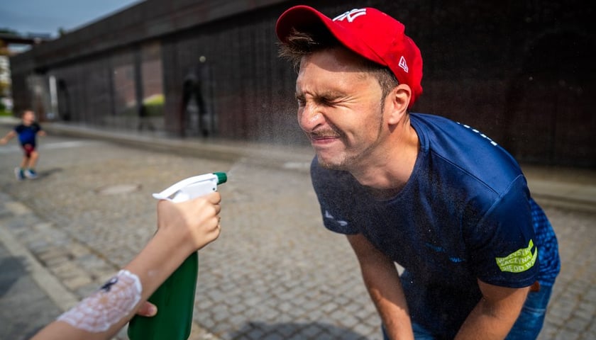 Twarz mężczyzny jest ochlapywana wodą ze spryskiwacza