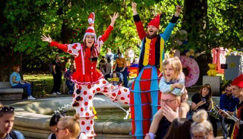 Dwoje ludzi przebranych w kolorowe krasnalowe stroje na tle wrocławskiego ratusza 