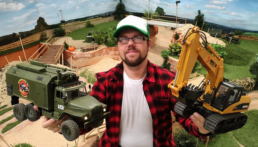 Marcin Leszczyński, właściciel Automanii RC z dwoma pojazdami w rękach - wojskowym (z lewej) i koparką (z prawej)