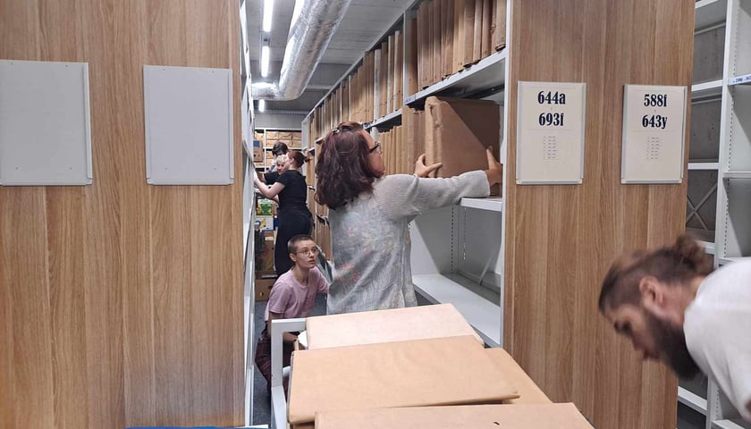 Kobieta i kilka osób pomiędzy regałami z książkami w Archiwum Archidiecezjalnym na Ostrowie Tumskim, 16 września 2024 roku