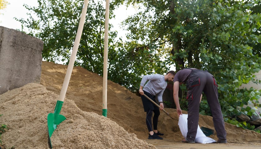 Mężczyźni sypiący piasek do worków