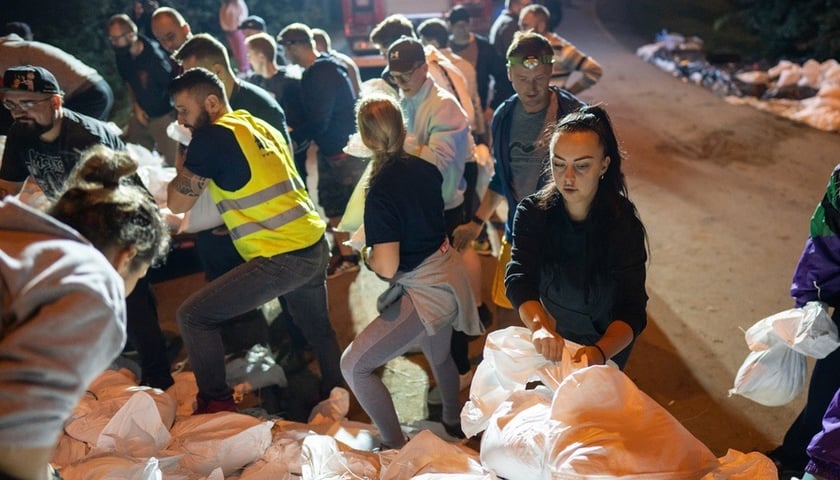 Kobiety i mężczyźni układają worki z piaskiem na Marszowicach w nocy z 17 na 18 września 2024 roku