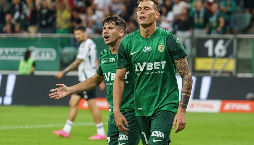 Sebastian Musiolik, za nim rozkładający ręce Petr Schwarz (w zielonych strojach) na murawie Tarczyński Areny podczas meczu z Legią (zdjęcie ilustracyjne)
